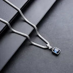 Silver necklace with a blue pendant on a dark surface
