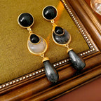 Pair of gold and black earrings on a wooden surface