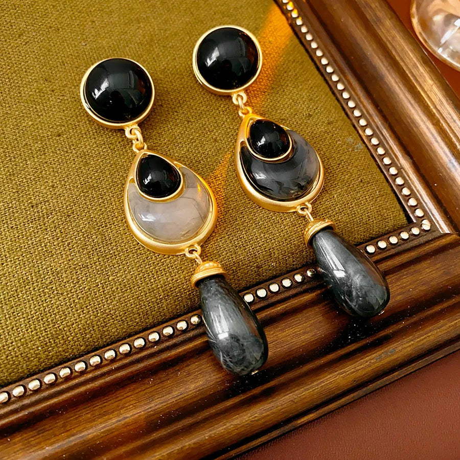 Pair of gold and black earrings on a wooden surface