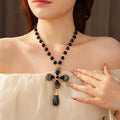 Woman wearing a black beaded necklace with a gold and black pendant.