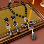 Jewelry set with black and gold necklace and earrings on a wooden surface