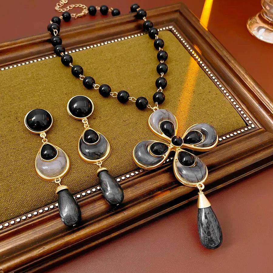 Jewelry set with black and gold necklace and earrings on a wooden surface