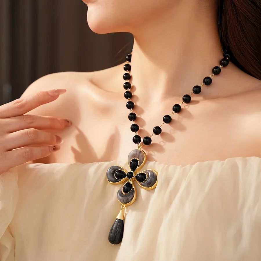 Woman wearing a black beaded necklace with a large flower pendant.