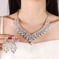 Silver necklace and earrings set on a plain background