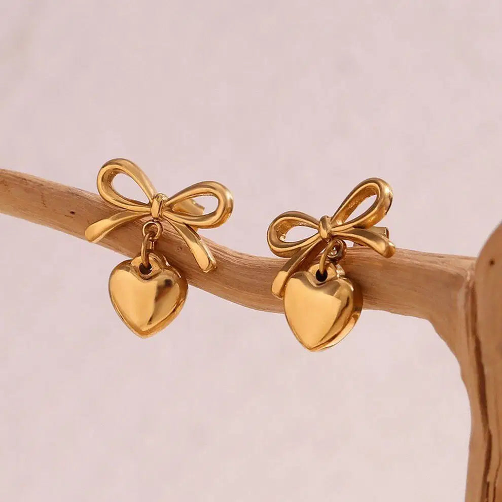 The Season of Bow Earrings stainless steel feature elegant gold-tone bows with dangling heart charms, perfect for stylish earrings lovers seeking modern fashion jewelry.