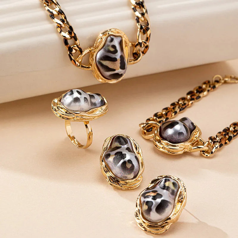 Gold jewelry set with black stones on a beige surface