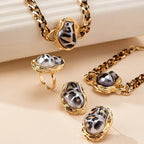 Gold jewelry set with black stones on a beige surface