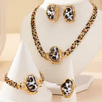 Gold necklace and earrings with black and white stones on a white stand.