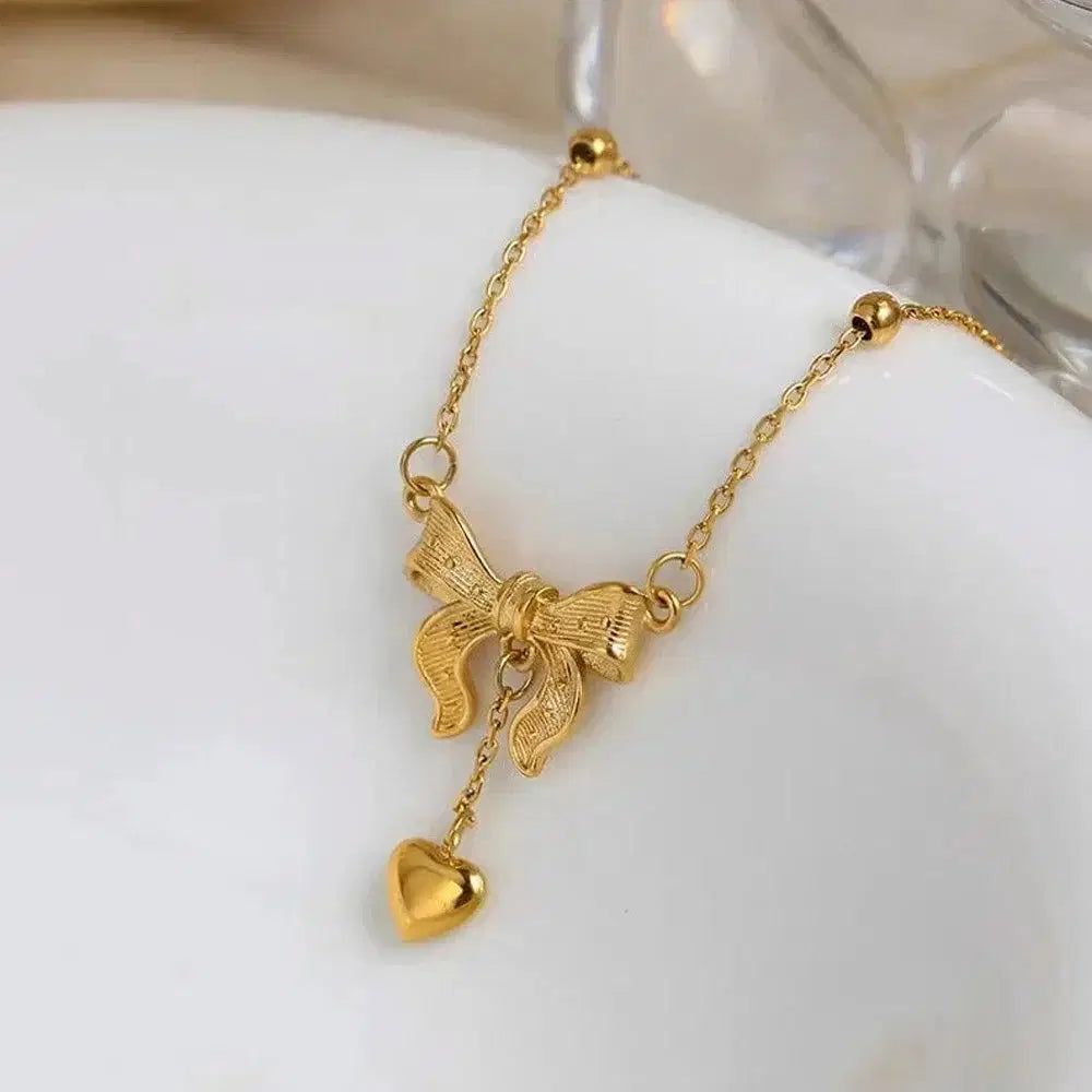 Golden Bow Knot Heart Tassel Pendant Necklace, Size: Free, featuring a delicate gold bow with a hanging heart charm on a fine gold chain, elegant fashion jewelry for women.