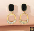 Gold earrings with black stones on a beige background