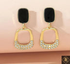 Gold earrings with black stones on a beige background