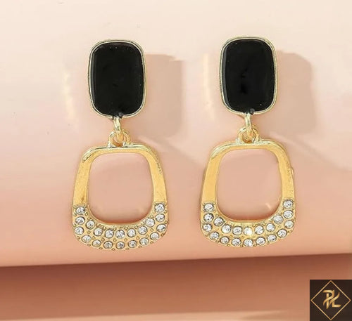 Gold earrings with black stones on a beige background