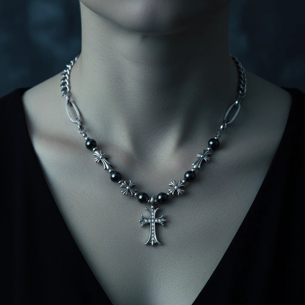 A gothic-style silver cross pendant necklace with dark beads and ornate star details, shown on a model's neck wearing a black top.