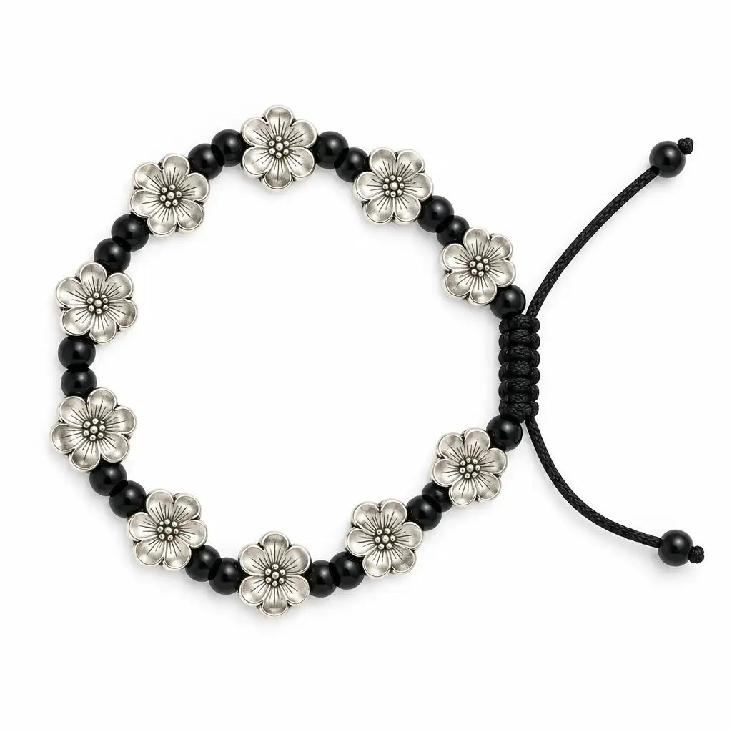 A beaded stretch bracelet featuring alternating black round beads and silver-toned flower-shaped beads, with a black adjustable cord closure, shown on a plain white background.