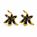 A pair of gold and black flower-shaped stud earrings on a clean white background.