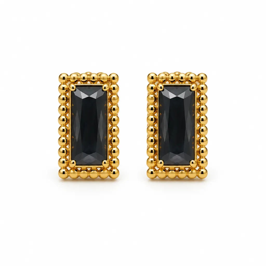 A pair of gold rectangular stud earrings featuring a faceted dark black gemstone in the center, surrounded by a border of small gold beads, set against a plain white background.