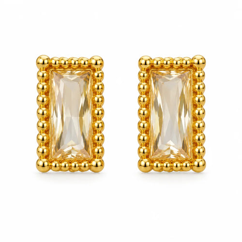 A pair of gold rectangular stud earrings featuring a faceted clear crystal center, surrounded by a raised beaded gold border, set against a plain white background.