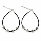 A pair of black beaded anklets with silver-tone flower charms and adjustable chain closures, displayed on a clean white background.