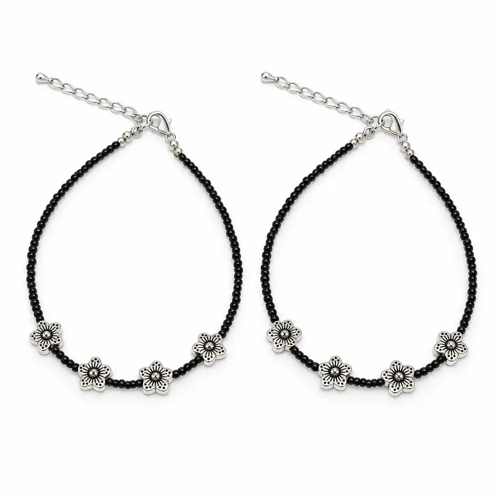A pair of black beaded anklets with silver-tone flower charms and adjustable chain closures, displayed on a clean white background.