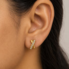 A close-up of a person's ear wearing a gold ear cuff earring adorned with small clear stones.